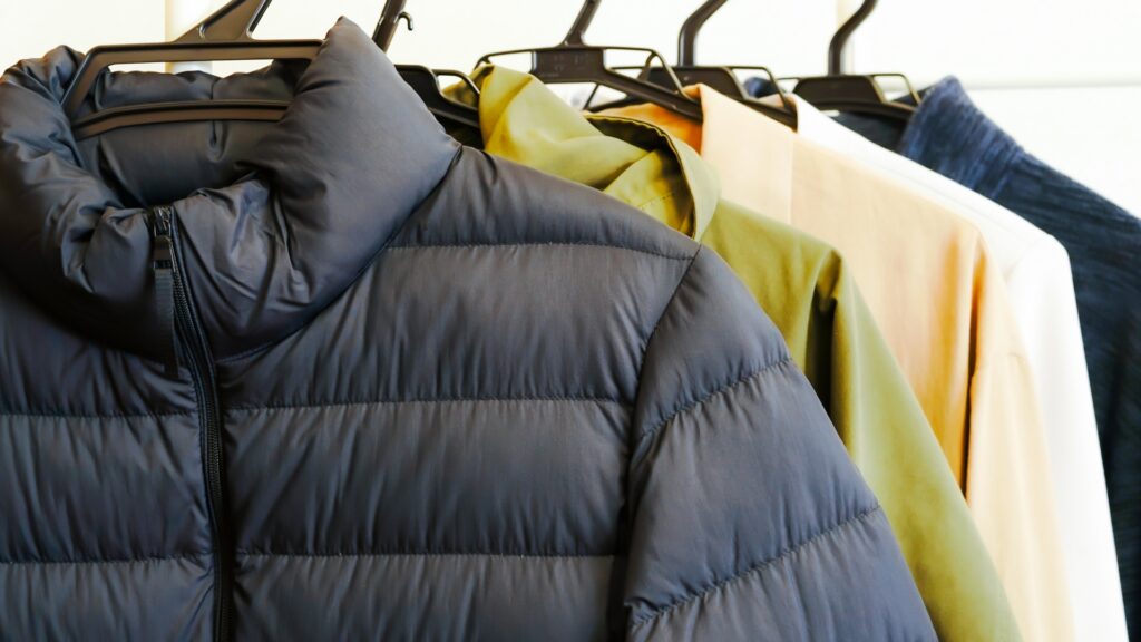 ハンガーにかけられた黒やカーキのダウンジャケットとアウター