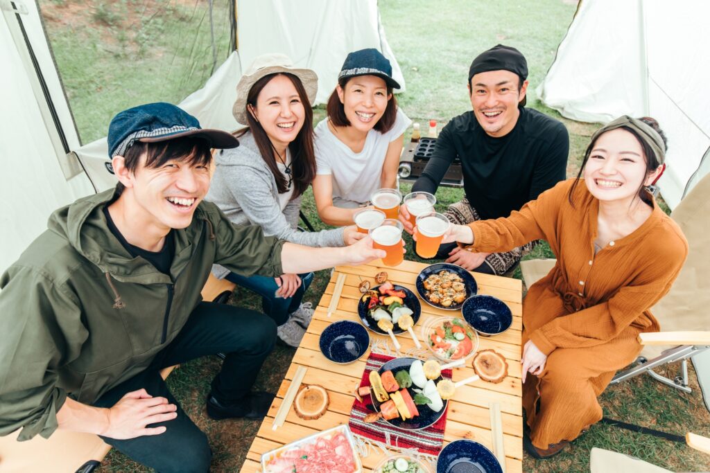 BBQと乾杯を楽しむグループキャンプの様子