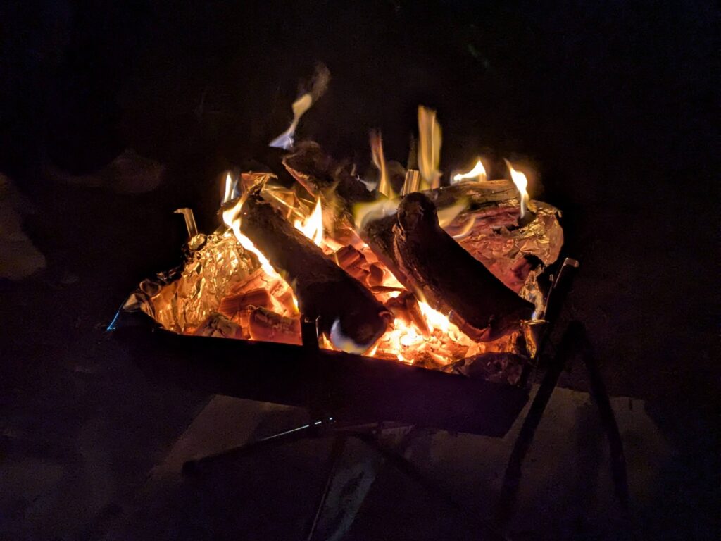 夜のキャンプ場でメッシュ越しの炎を楽しむ焚き火の時間