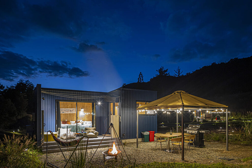 焚き火台と専用BBQスペースを備えた独立型キャビン（コンテナハウス）の幻想的な夜の風景