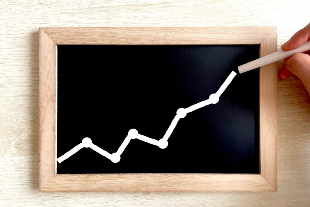 資産の増加や業績が短期的には上下しながら好調に伸びていく様子を示す、右肩上がりのグラフのイメージ
