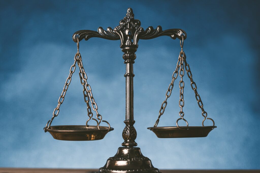 青い背景に置かれた、アンティーク調の金属製の天秤