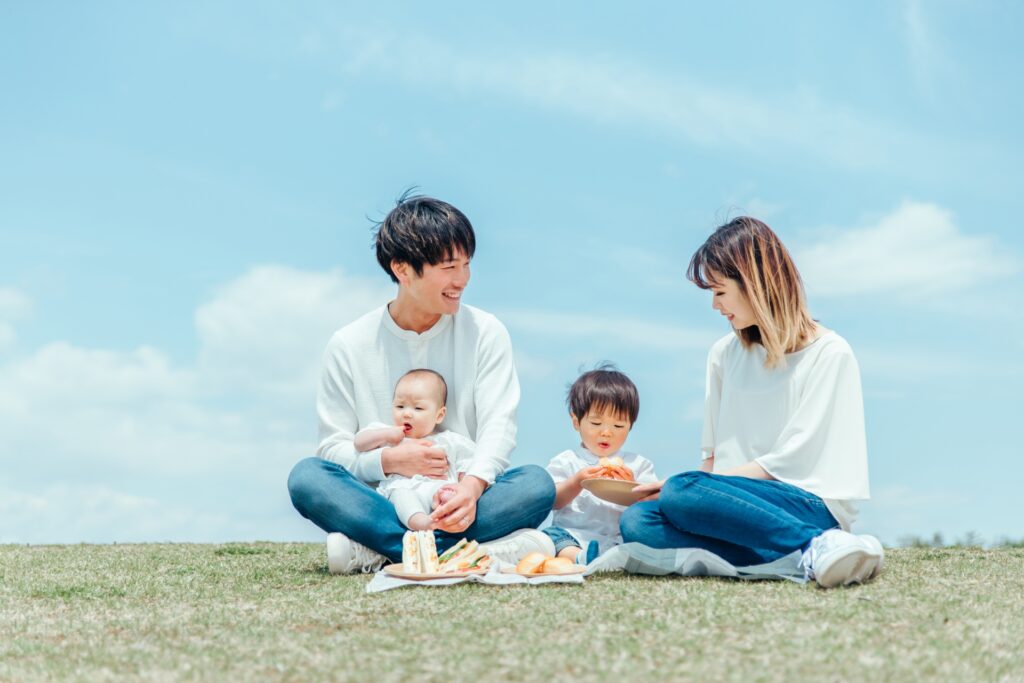 青空の下、芝生の上でピクニックを楽しむ4人家族